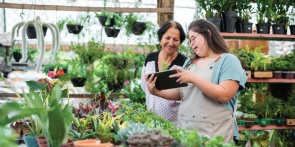 Two ladies in a greenhouse looking at a tablet